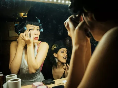 Cabaret dancers getting ready in front of a mirror in Paris, France.
