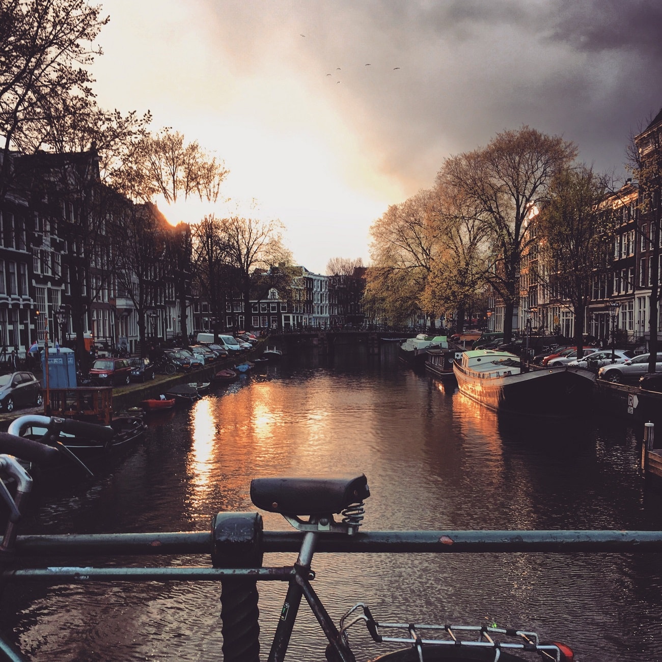 A bicycle parked on the side of a bridge over the canal in Amsterdam