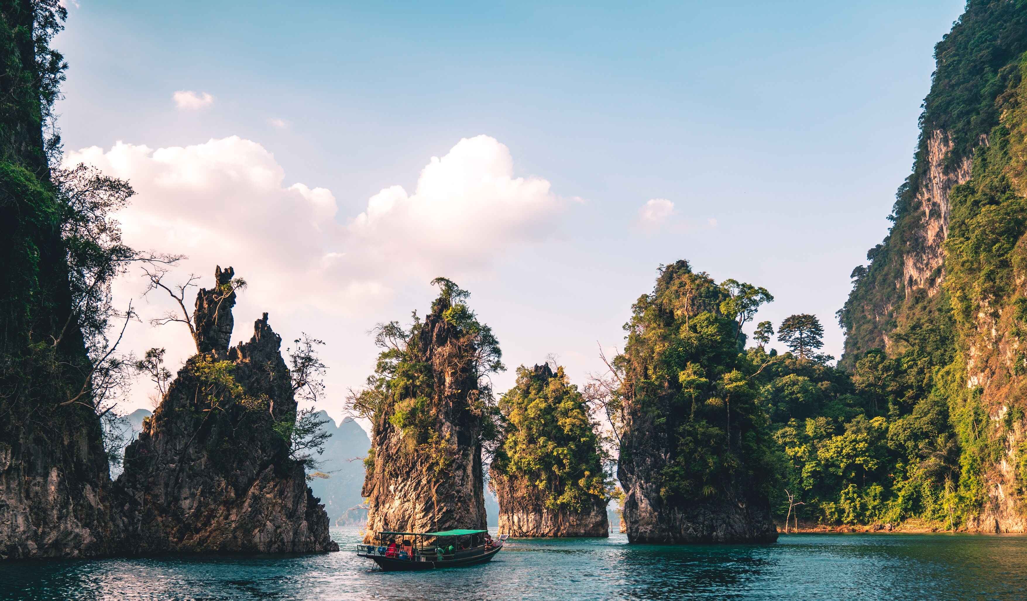 Traditional boat passing small rocky islands in Thailand