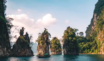 Traditional boat passing small rocky islands in Thailand