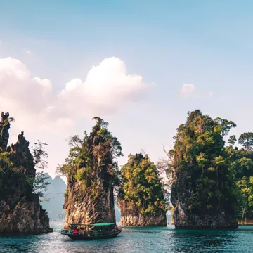 Traditional boat passing small rocky islands in Thailand