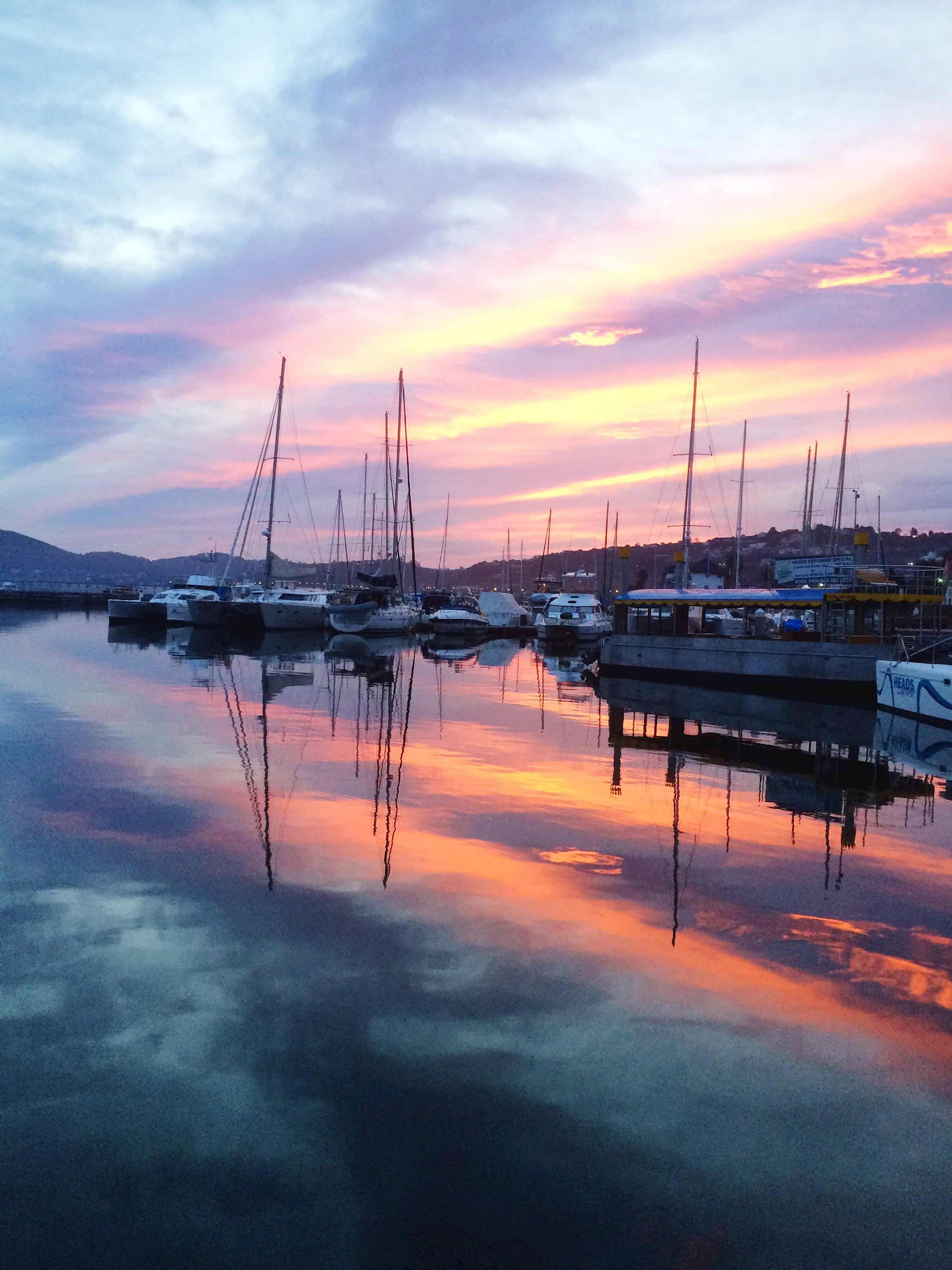 Knysna marina with sailboats reflecting on calm water at sunset in South Africa