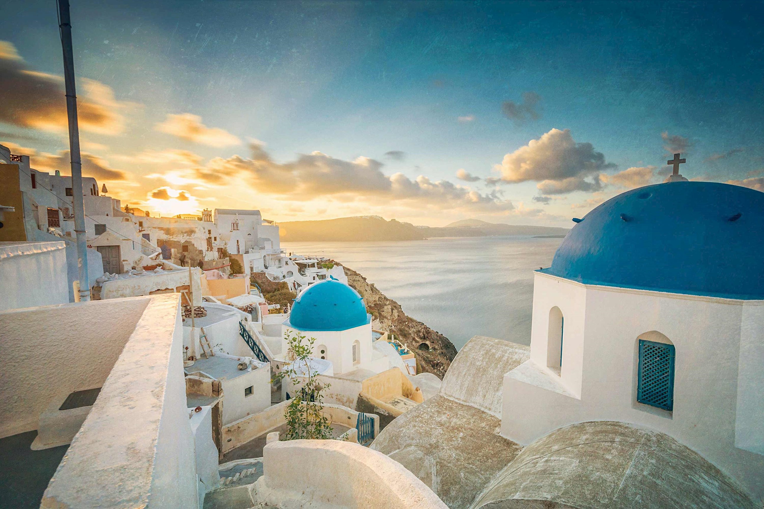 Sunset over whitewashed buildings and blue-domed churches in Santorini, Greece