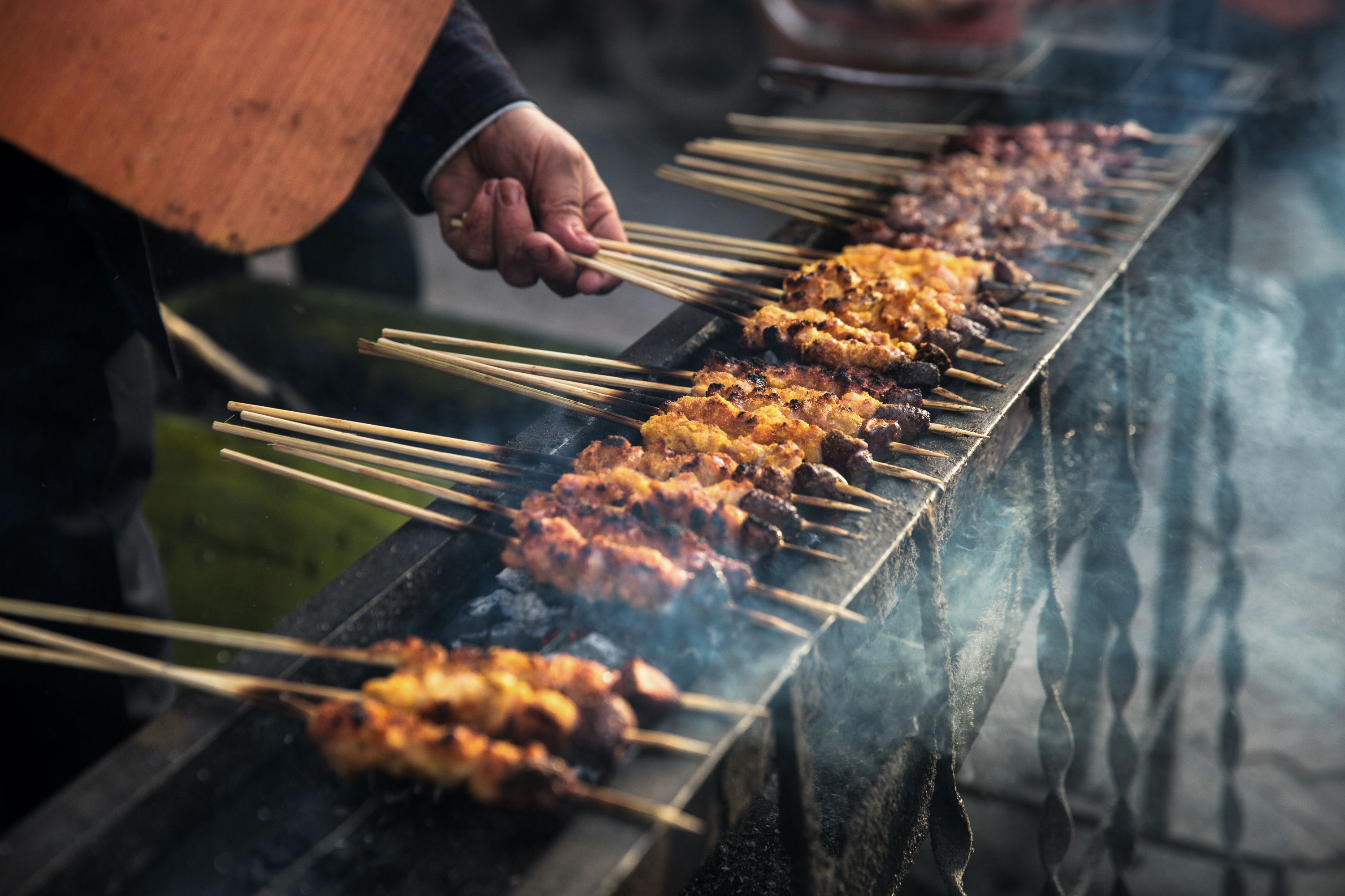 Skewers of meat cooking over a smoky grill, a typical food in China