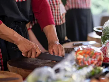 Close-up of chef demonstrating correct knife grip on cutting board