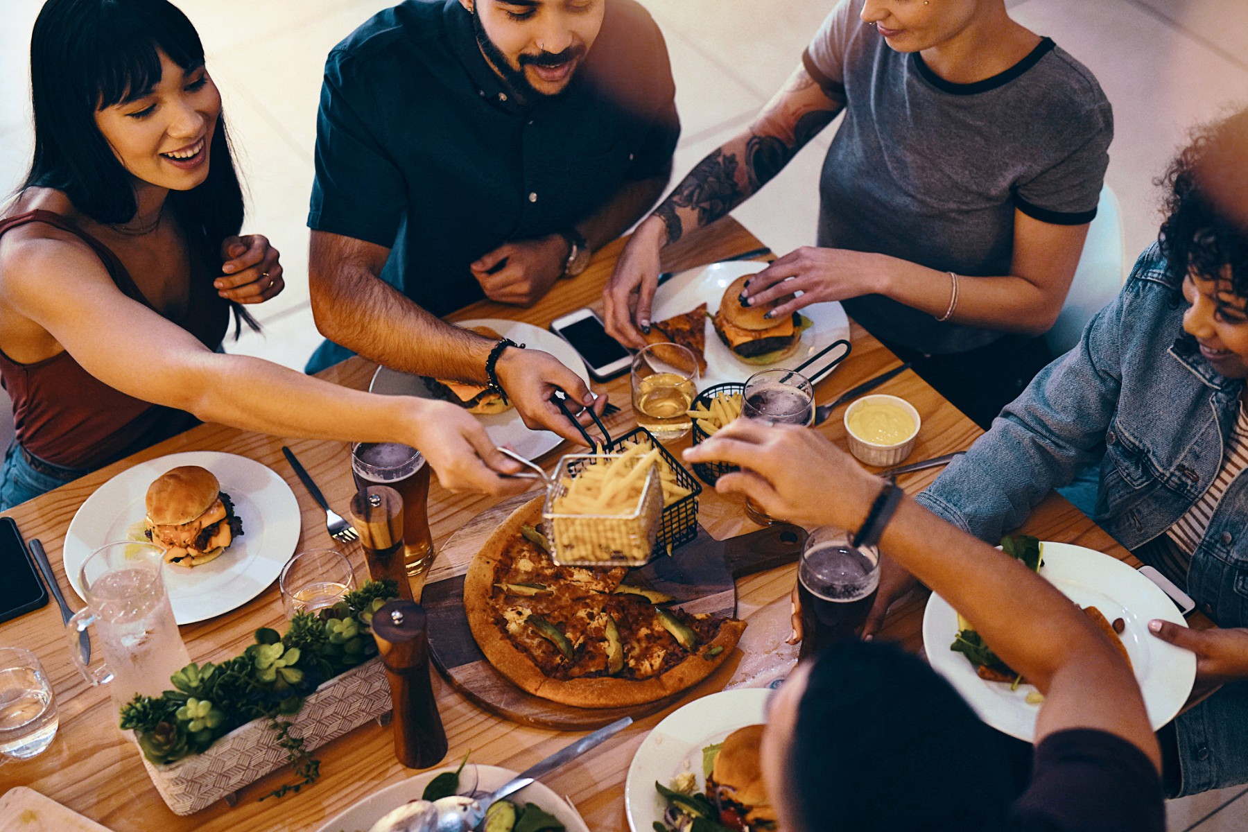 People eating burgers, chips and pizza at a restaurant