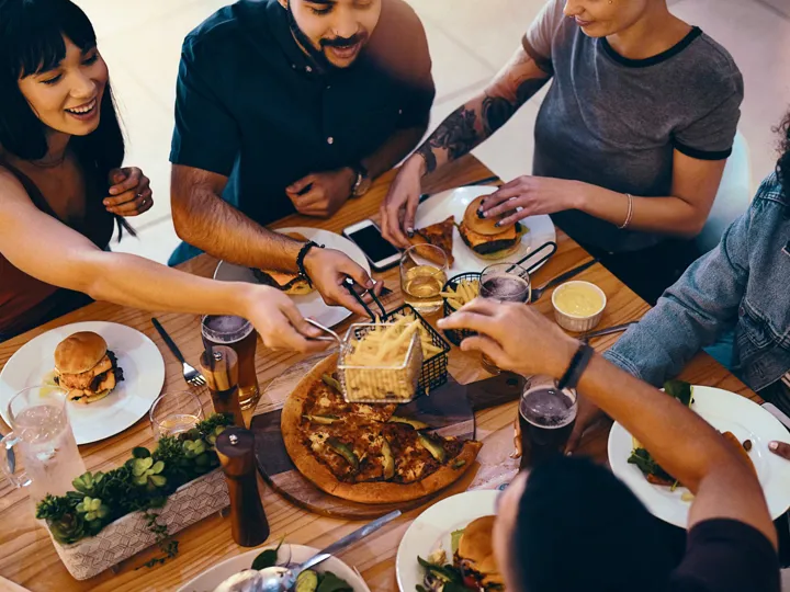 People eating burgers, chips and pizza at a restaurant