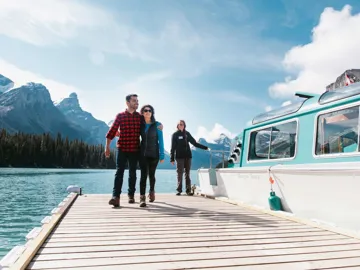 Three people stepping off a boat onto a jetty at Maligne Lake, Canada