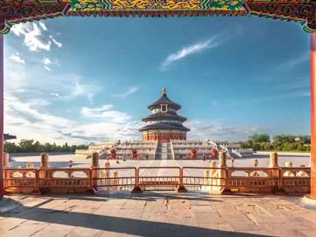 A round temple building with a golden orb on the top of the roof and a long set of steps leading up to it, the Temple of Heaven in China.