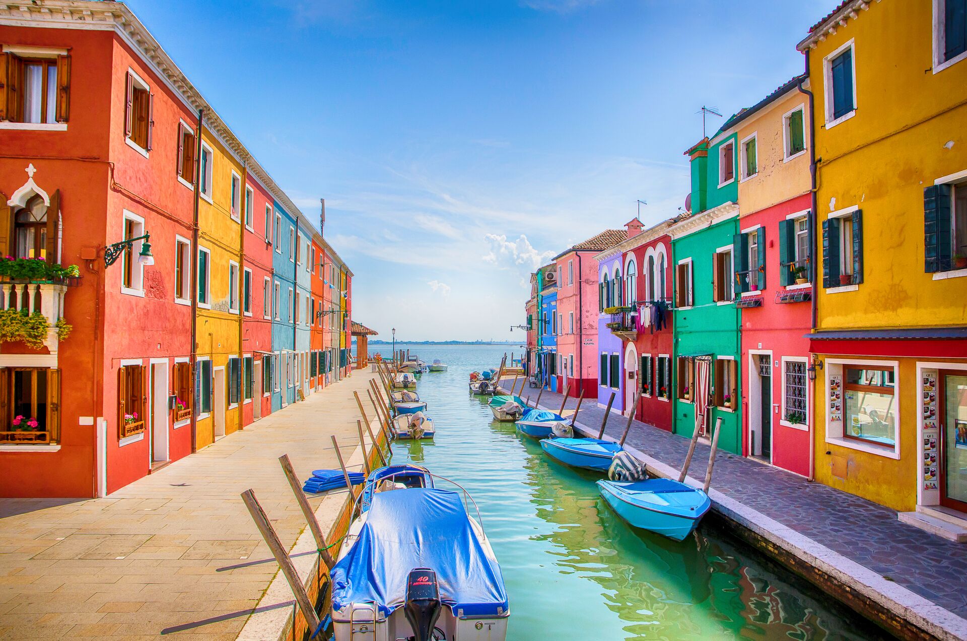 Boats and row of colorful buildings next to a river in Venice Italy