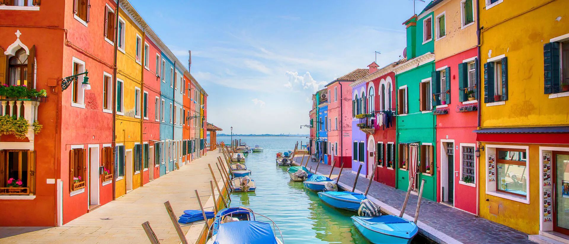 Boats and row of colorful buildings next to a river in Venice Italy