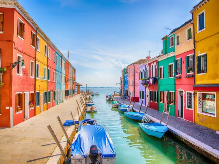 Boats and row of colorful buildings next to a river in Venice Italy