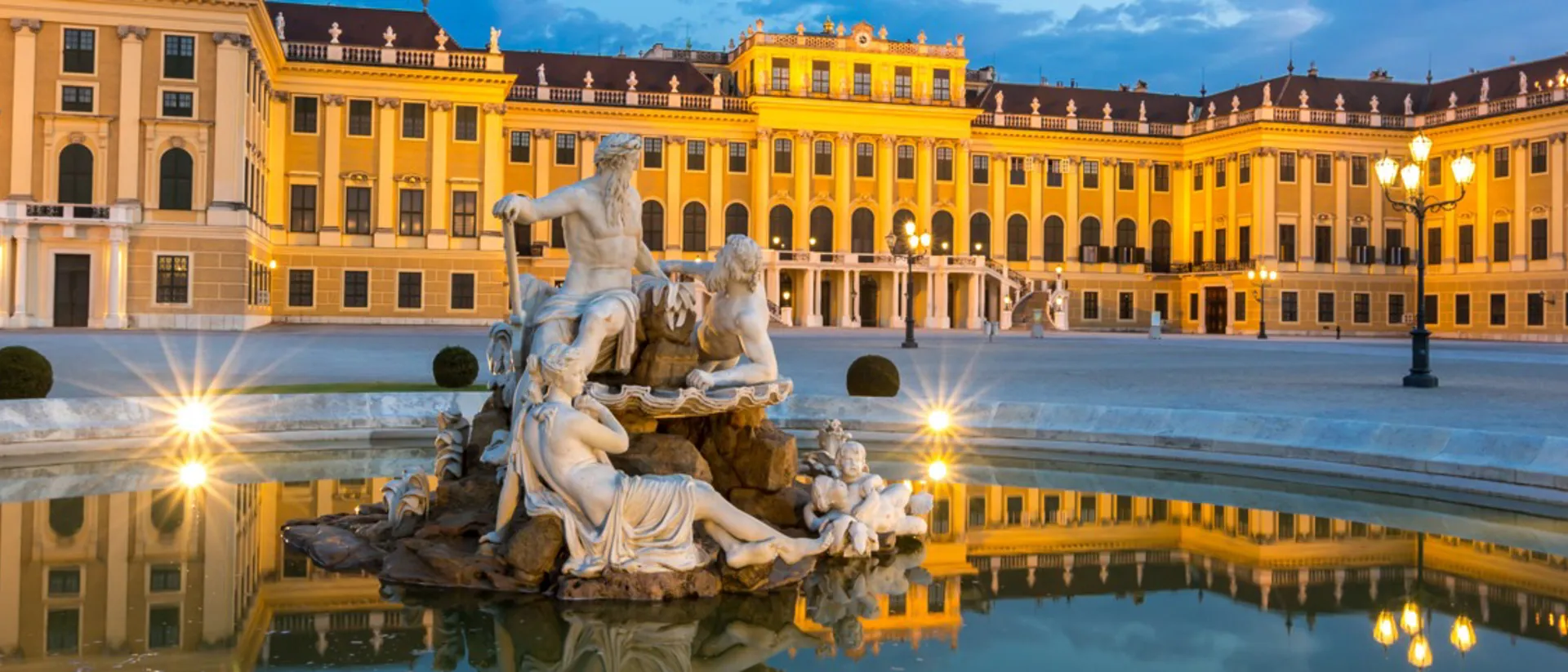 A fountain in front of a large building in Vienna Schonbrunn