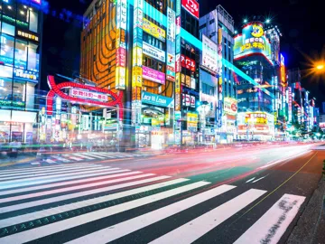 Night view of Shinjuku street with neon lights and busy crosswalk in Japan