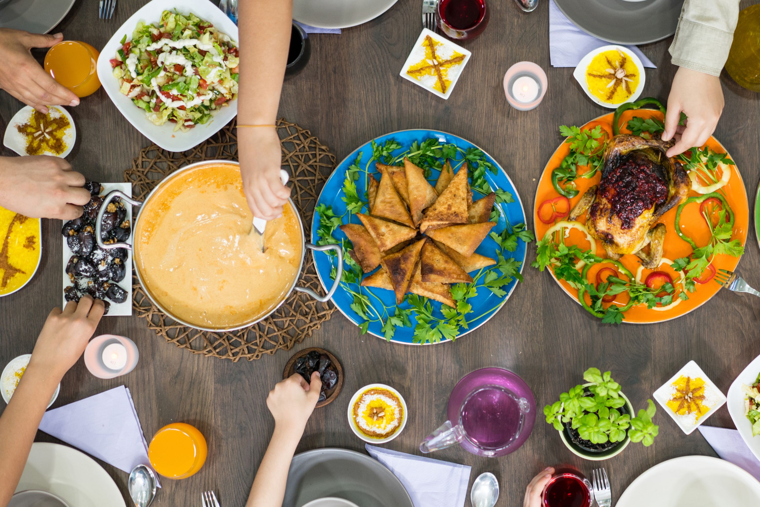Hands reaching for colourful plates of traditional Bosnian food arranged on a table top