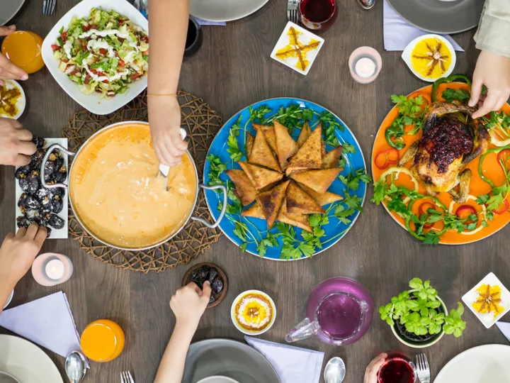 Hands reaching for colourful plates of traditional Bosnian food arranged on a table top