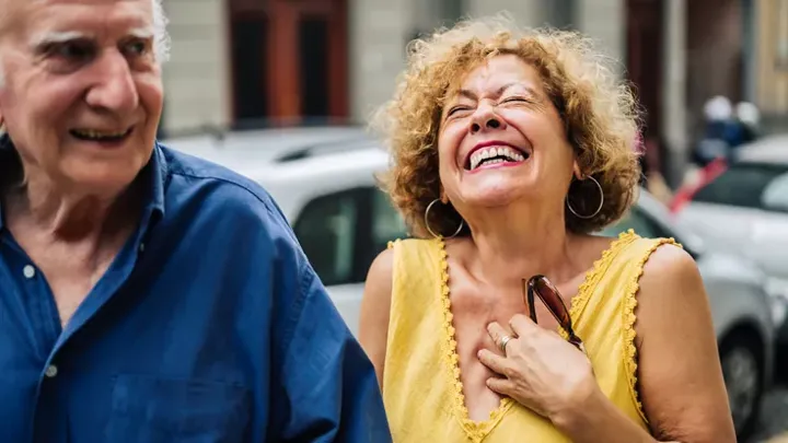 Hispanic elderly woman laughs while talking to her husband