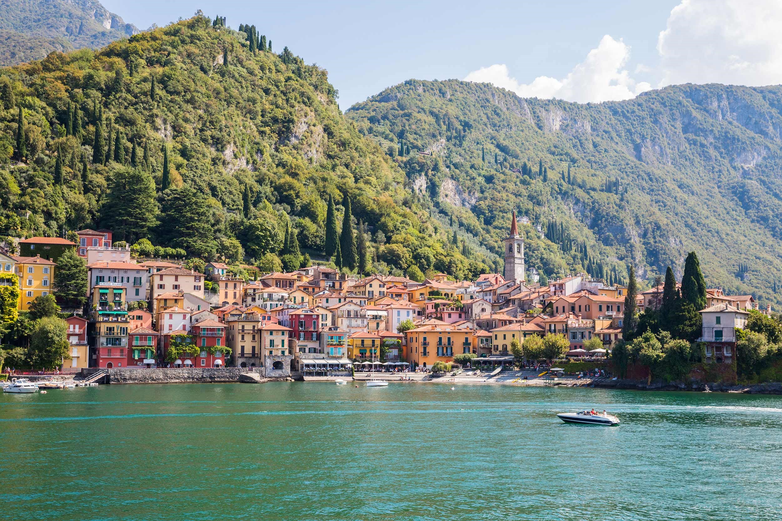 Scenic waterfront village surrounded by lush hills and clear water in Lake Como, Italy