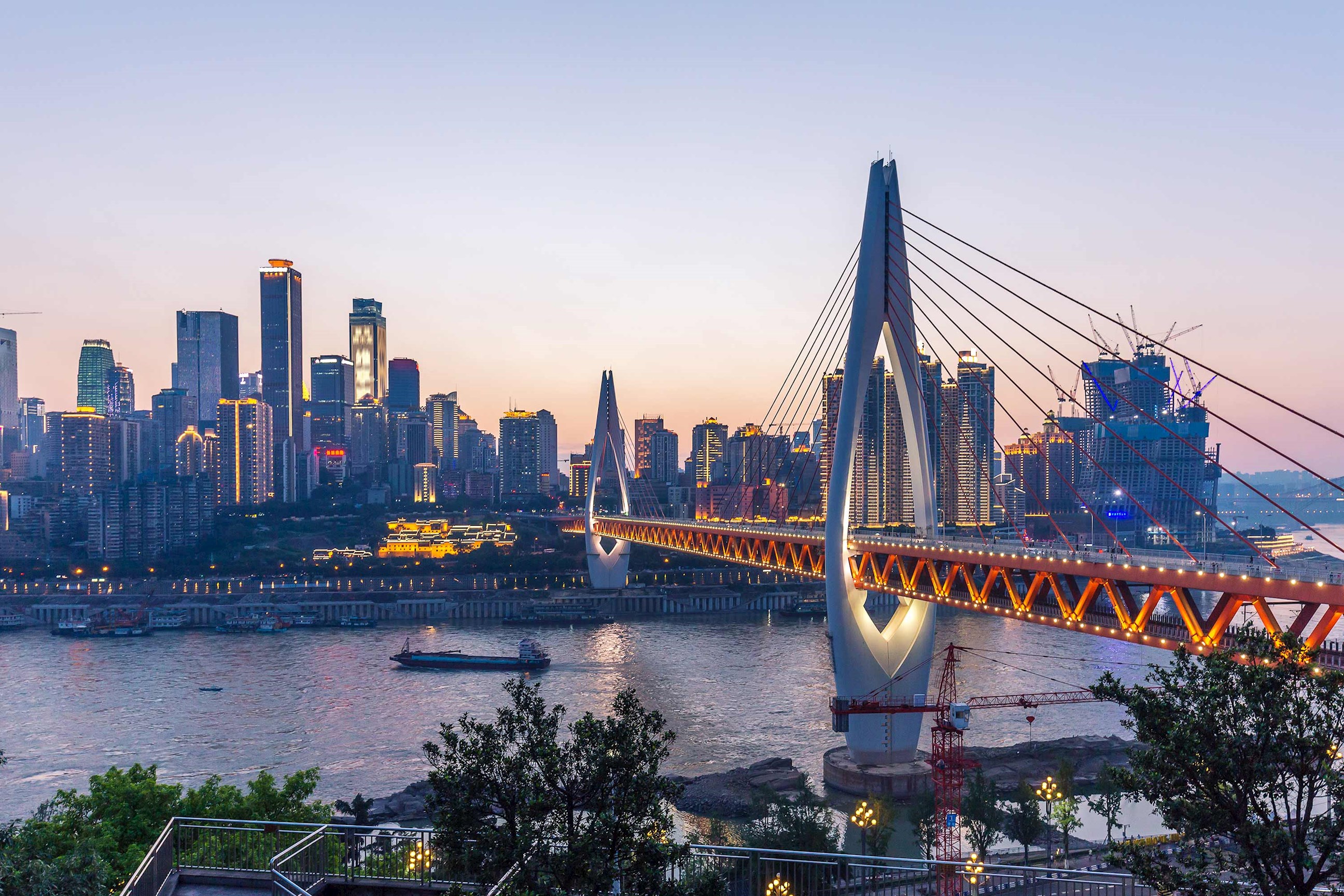 Chongqing skyline at sunset with illuminated cable-stayed bridge over Yangtze River