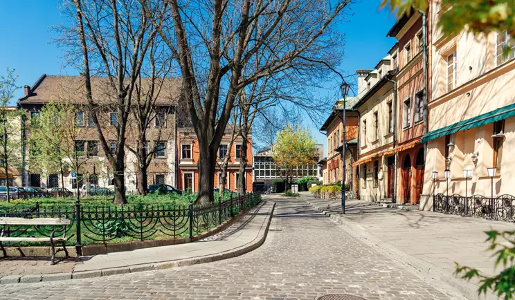 A cobblestone street lined with buildings and trees in Poland Krakow Jewish District