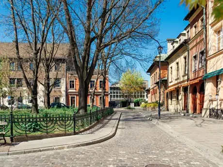 A cobblestone street lined with buildings and trees in Poland Krakow Jewish District