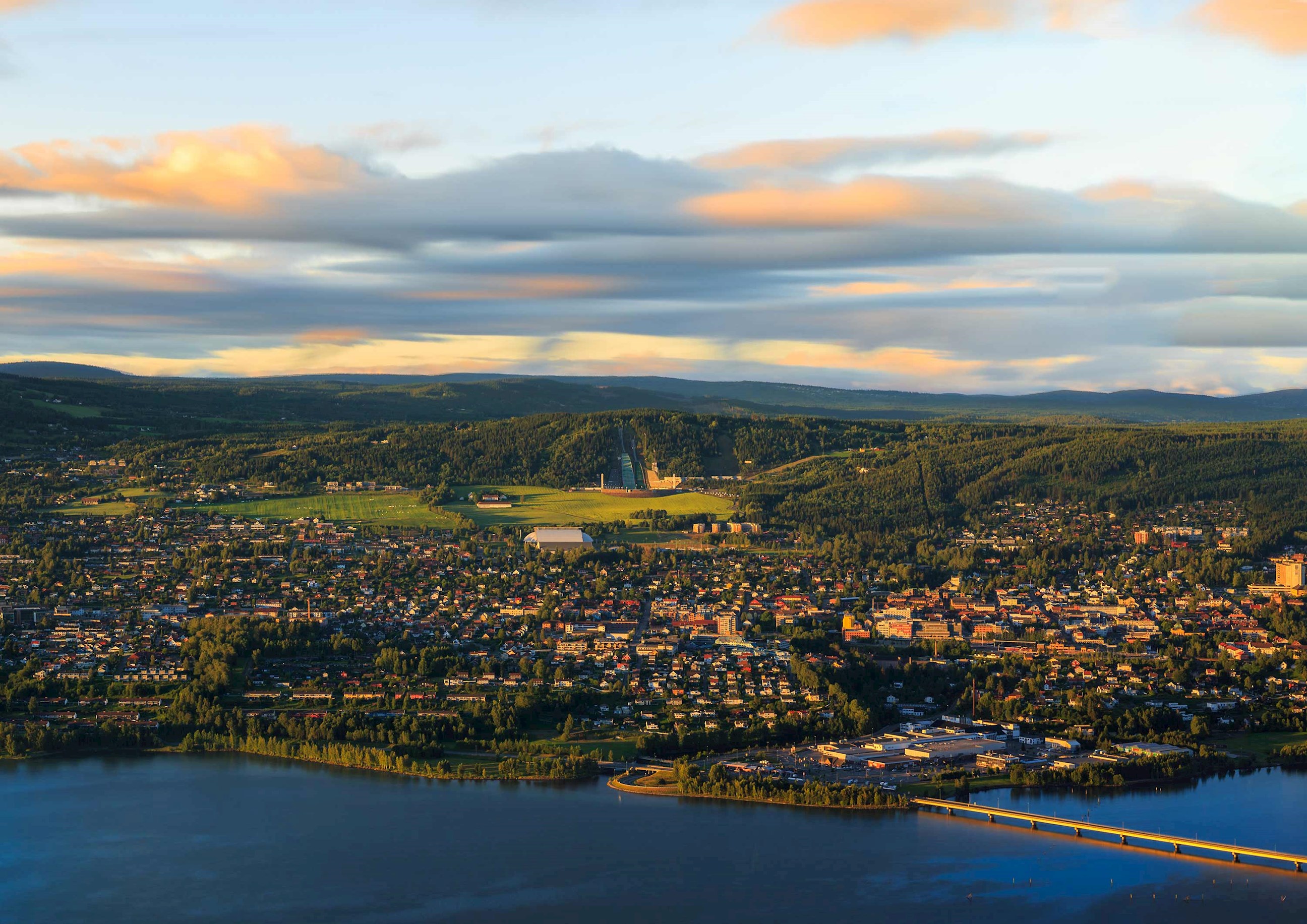 Aerial view of town surrounded by hills and water at sunset in Lillehammer, Norway