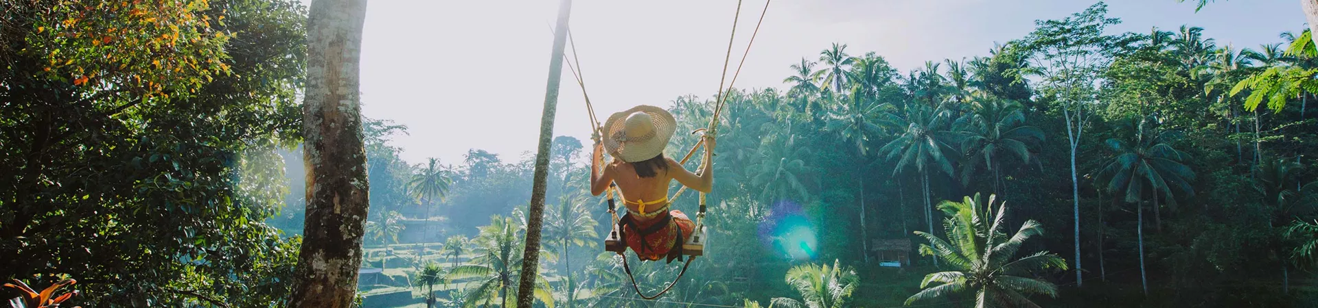Woman on a swing among palm trees