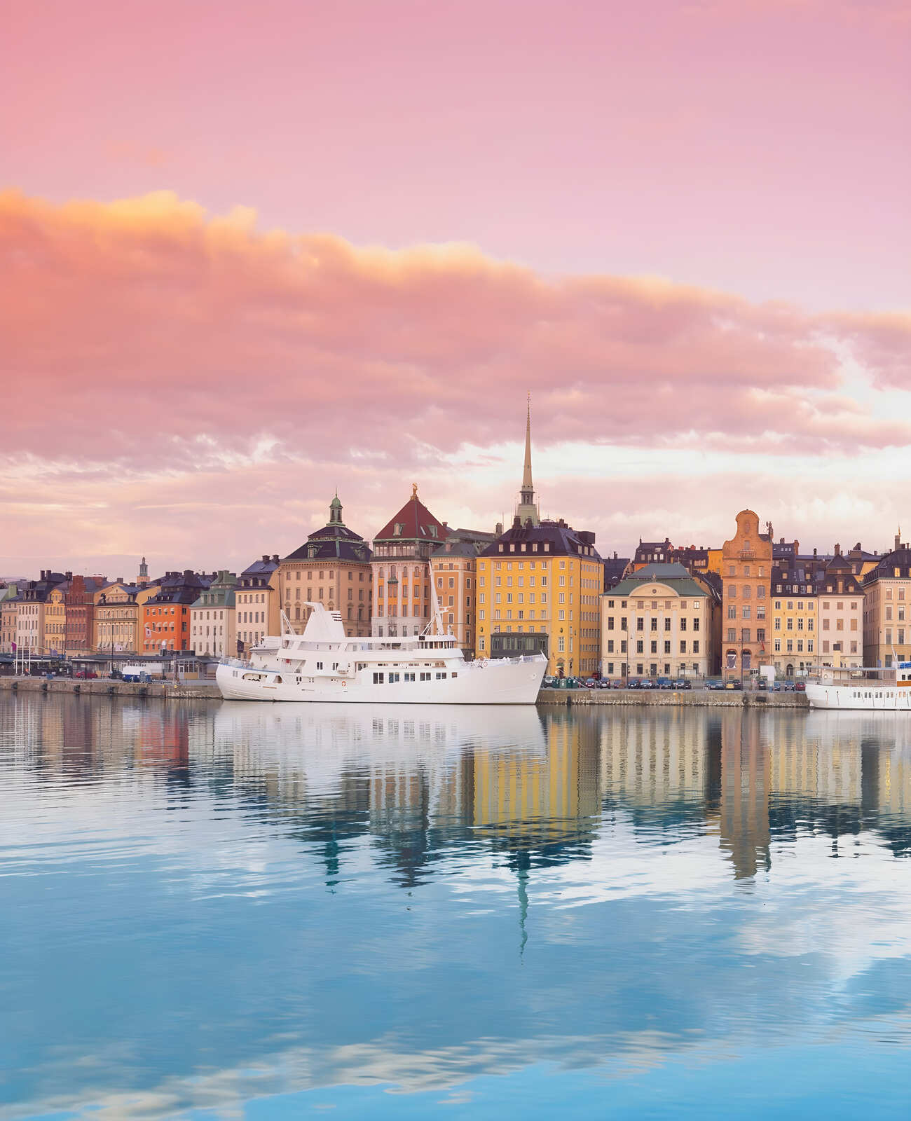 A large white boat moored on a river with a backdrop of beautiful buildings in Stockholm, Sweden