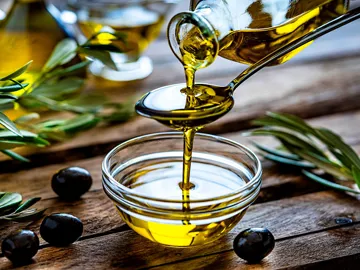 Pouring extra virgin olive oil into a glass bowl