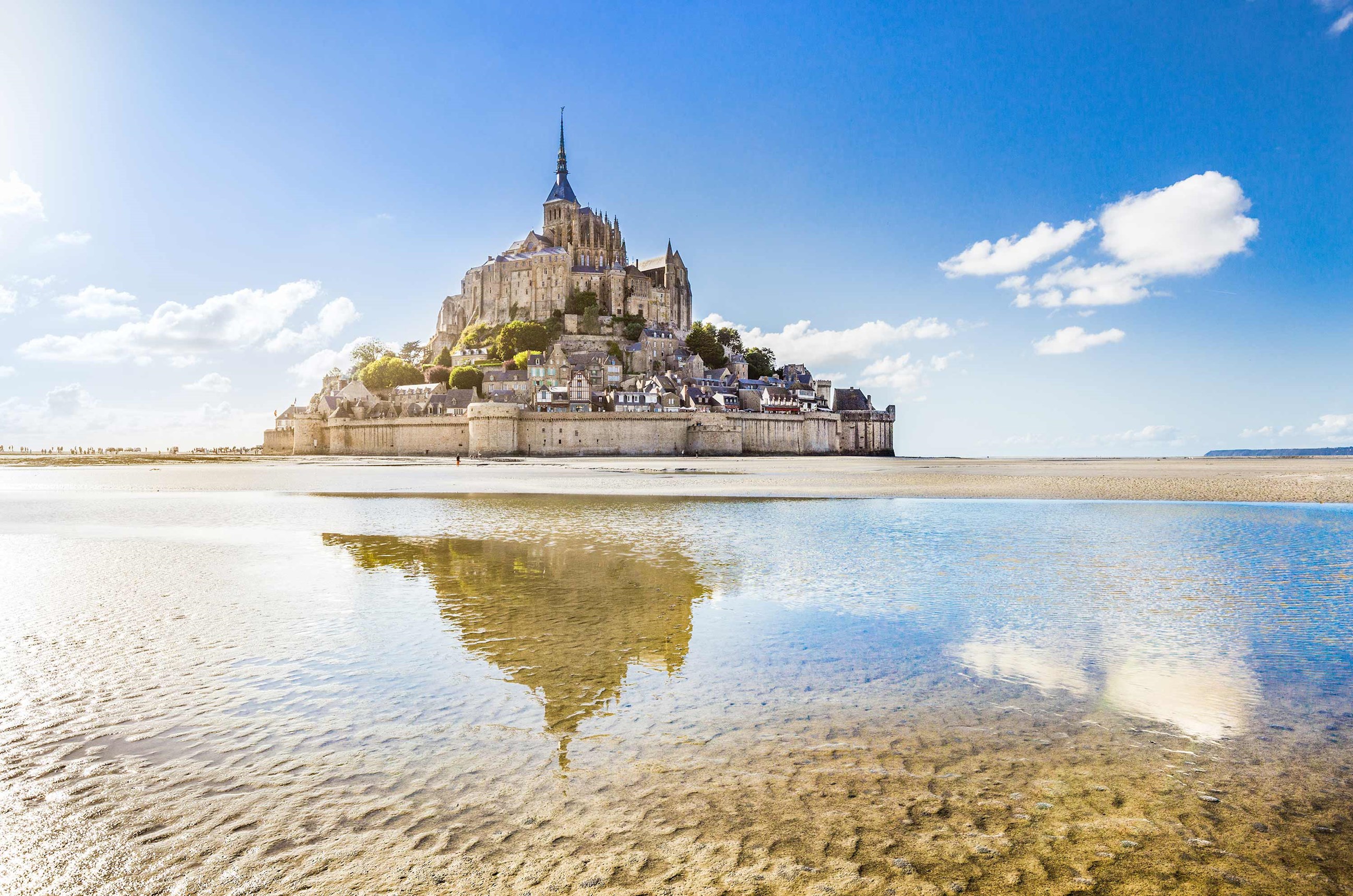 Mont-Saint-Michel reflected in tidal sands under clear skies in Normandy, France