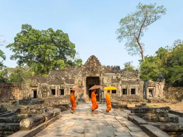 Monks in orange robes walking through an ancient stone temple