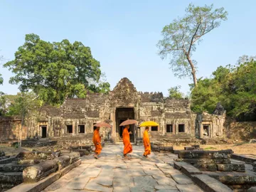 Monks in orange robes walking through an ancient stone temple