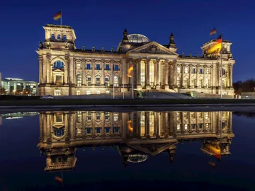 The Reichstag illuminated at night with reflection in water in Berlin, Germany