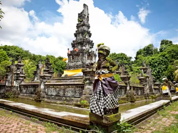 Pura Jagatnatha Temple with stone statues dressed in checkered cloth in Bali, Indonesia