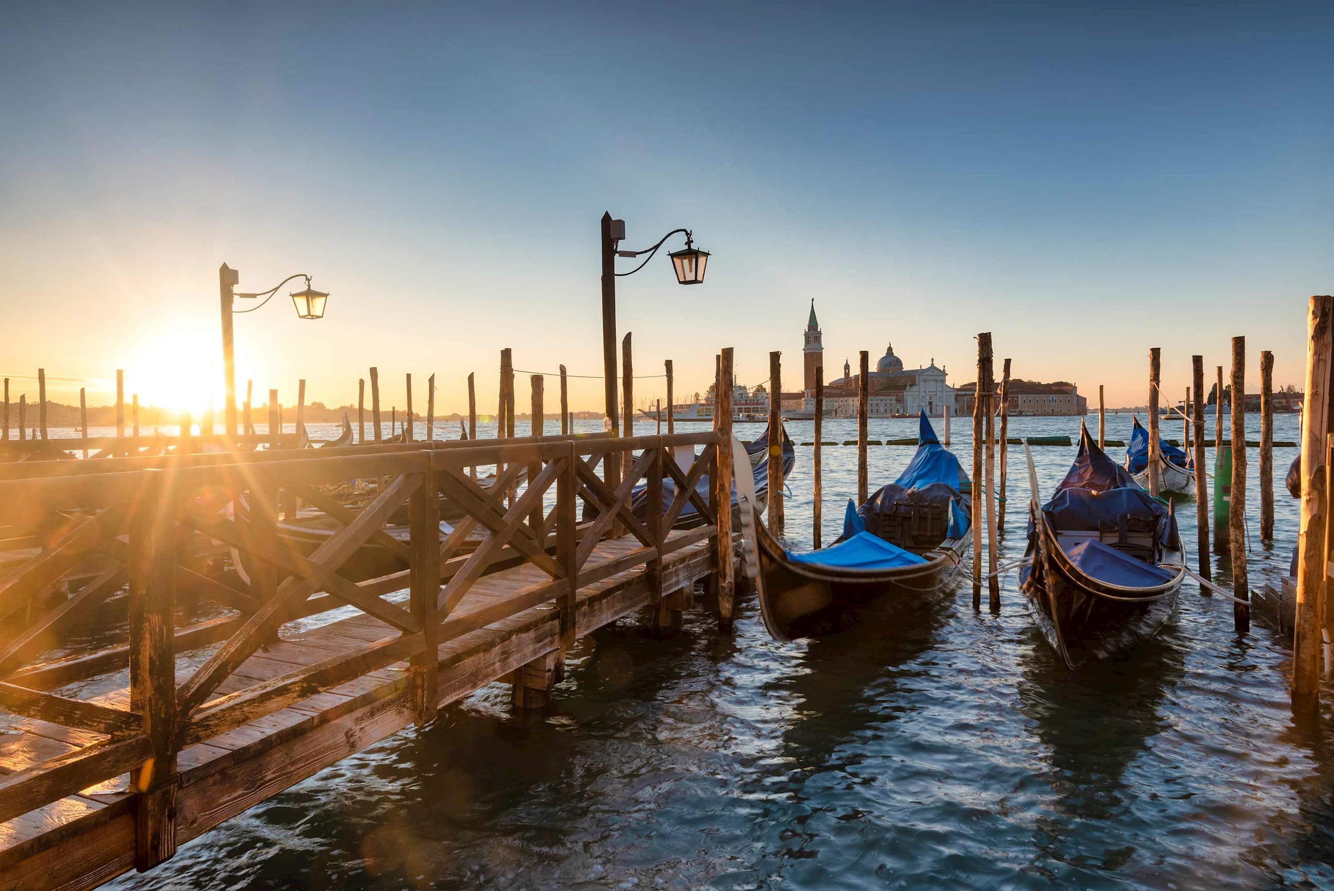 Row of gondolas docked together at sunset in Venice, Italy