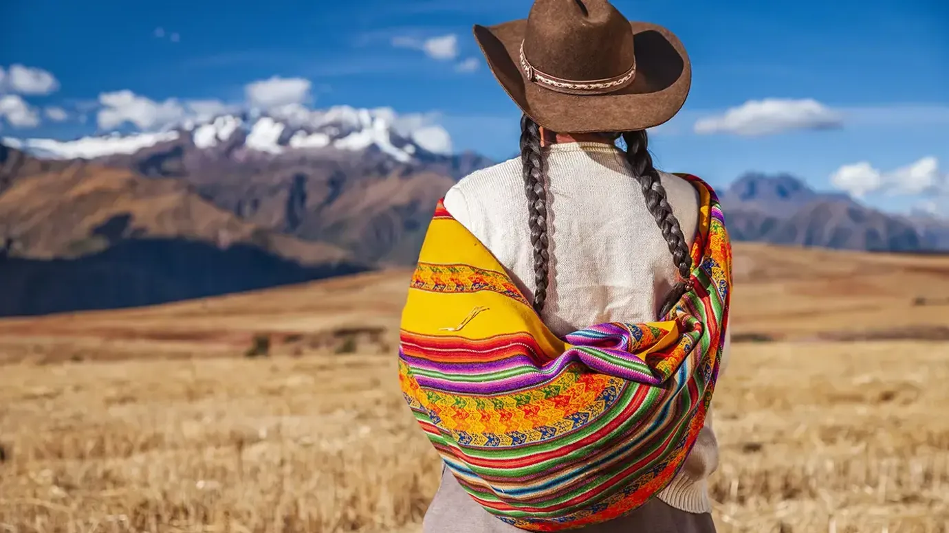 The back of a Peruvian woman in traditional clothing Andes against the landscape, The Sacred Valley