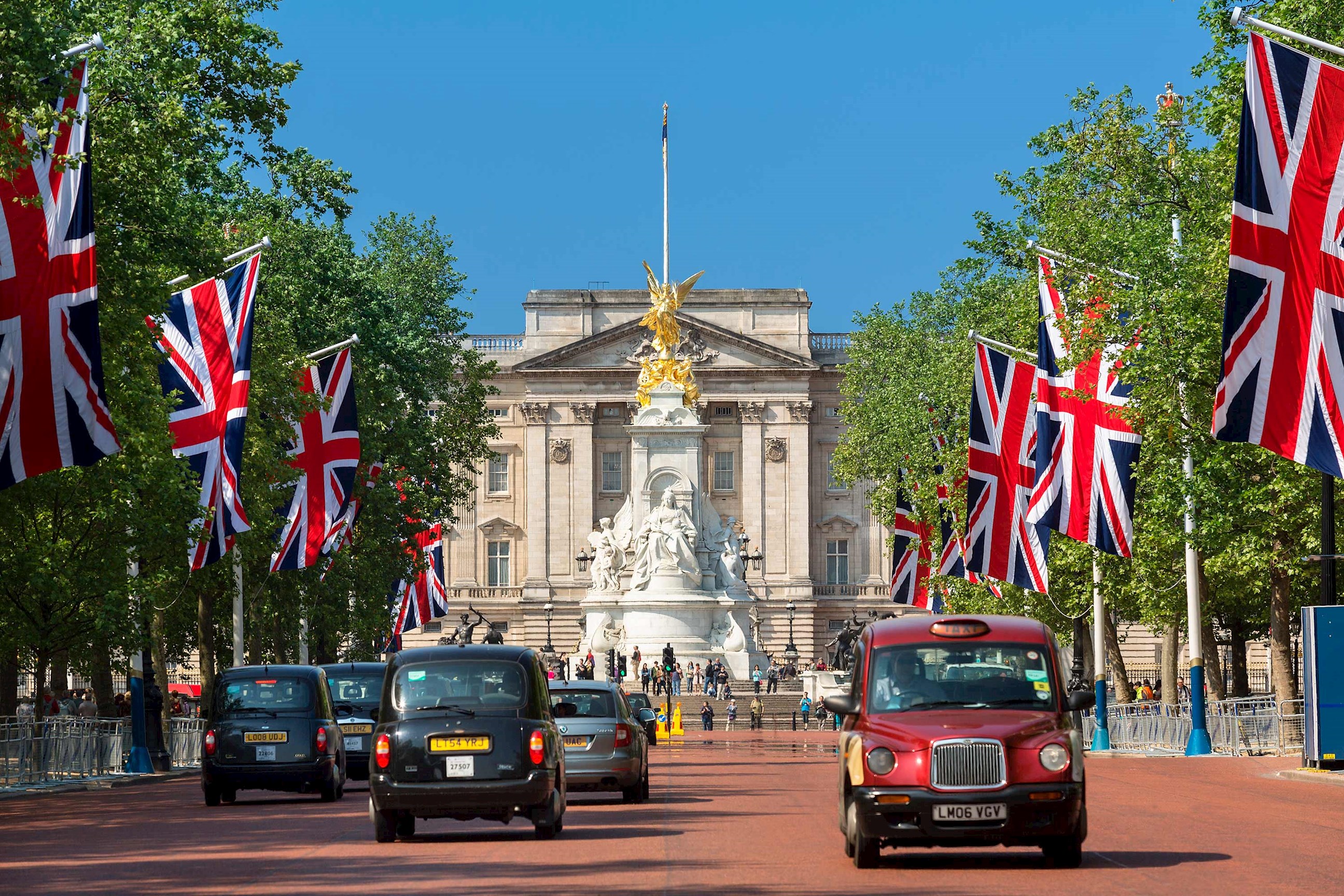 A street view of flags and vehicles under clear sky in London, England