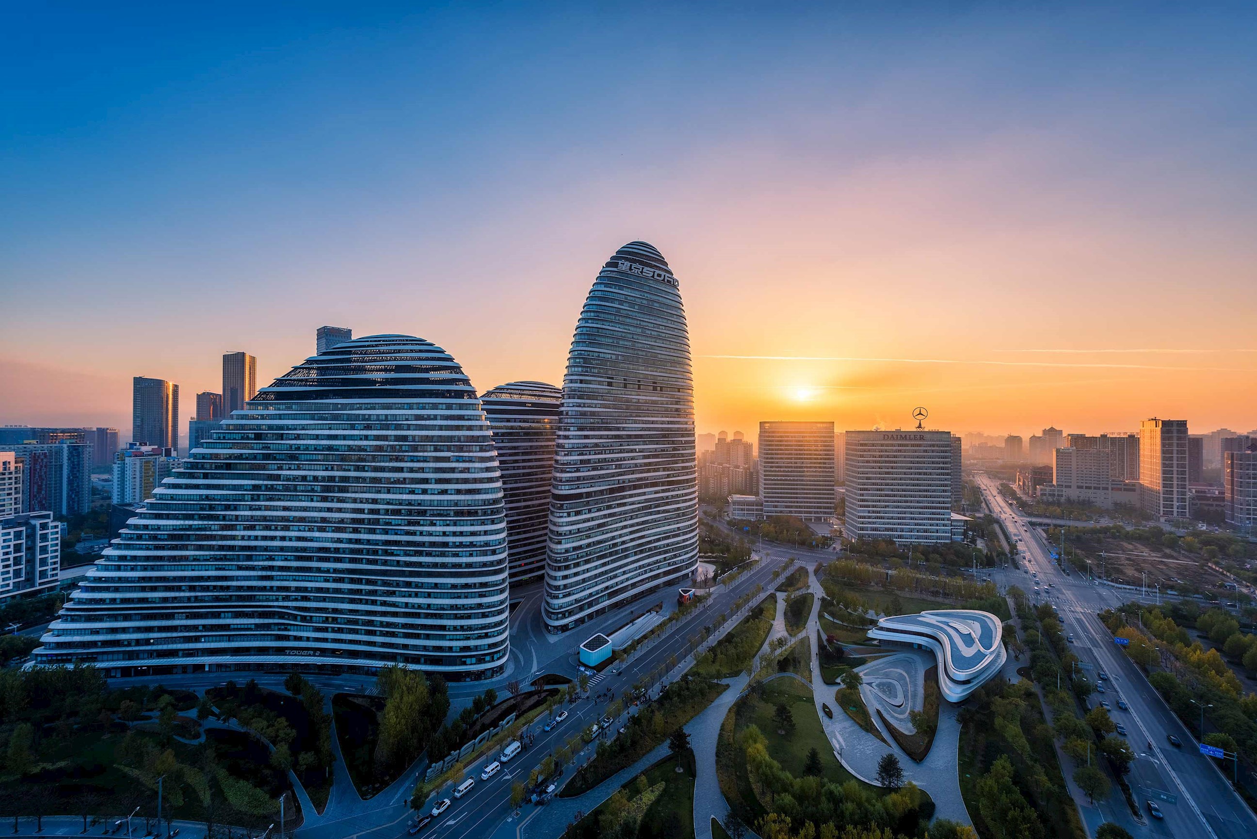 Modern curved skyscrapers with city roads and green spaces at sunrise in Beijing, China