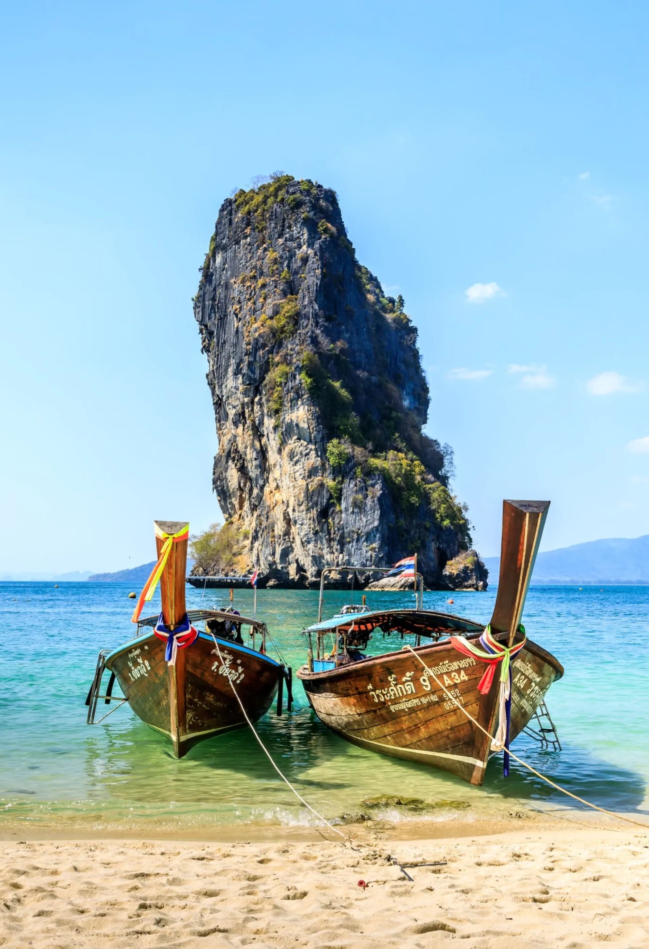 Boats on a beach with rock in background, Thailand