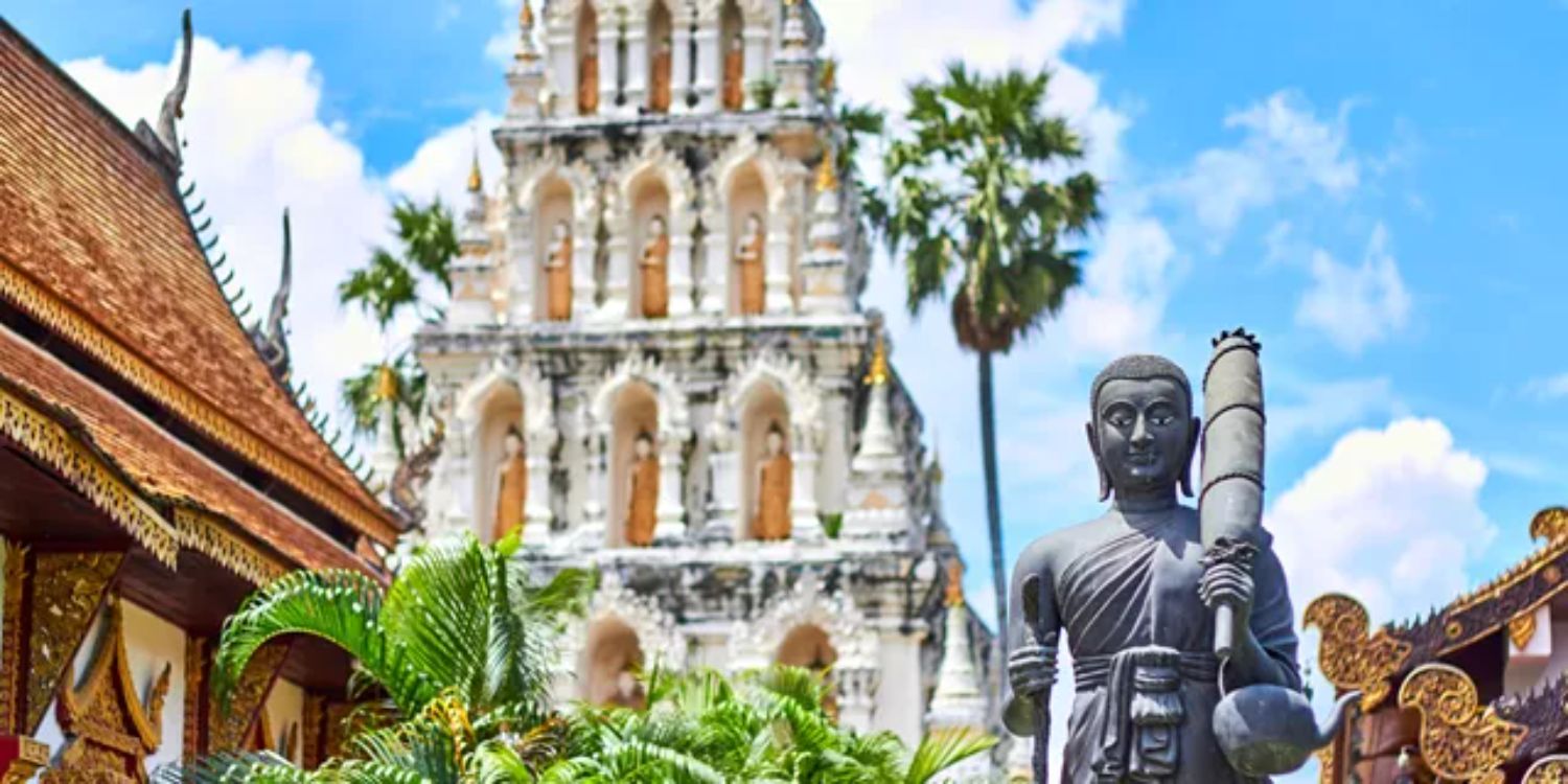 White ornate Temple with statue in foreground in Bangkok Thailand