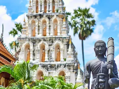 White ornate Temple with statue in foreground in Bangkok Thailand